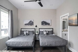 Ein Schlafzimmer mit zwei Betten, einem Deckenventilator und zwei Wandbildern im Bauernhausstil.
