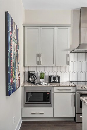 A modern kitchen with white cabinets, a microwave, a toaster, and a coffee maker on the countertop.
