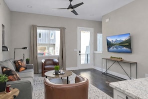 A modern living room with a sofa, armchair, coffee table, and a TV mounted on the wall.
