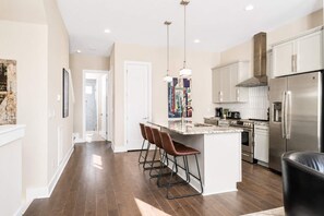 A modern kitchen with a central island, stainless steel appliances, and pendant lighting. - Two Luxury Homes • Side-by-Side • Sleeps 24 (Nashville)