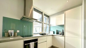 Una cocina moderna con horno integrado, una ventana y una cafetera.