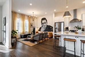 A modern kitchen with a stainless steel refrigerator, a gas stove, and a large island with stools.