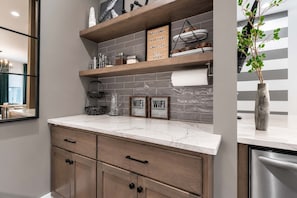 A kitchen with marble countertops, wooden cabinets, a hanging plant, and a sign that says 'WELCOME TO THE MUSIC CITY XOXO'.