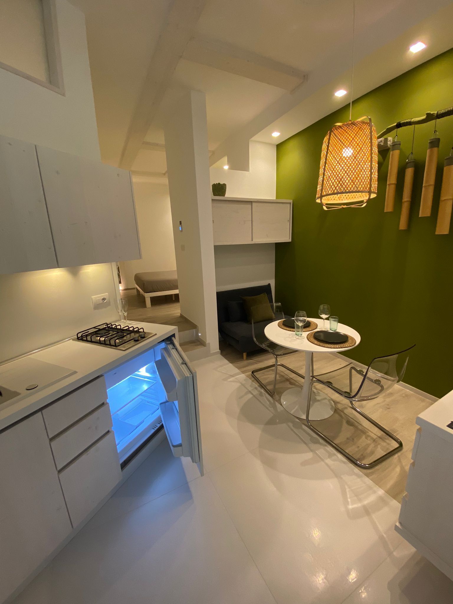 Una cocina moderna con estufa a gas integrada, un comedor con una mesa redonda y sillas, y una pared de acento verde.