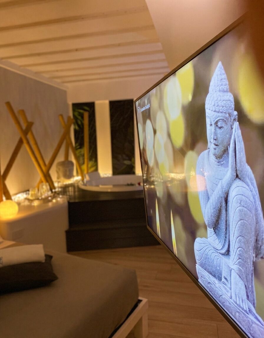 A modern interior with a large flat-screen TV displaying a statue, a wooden bench, and a minimalist decor with wooden beams and abstract art.