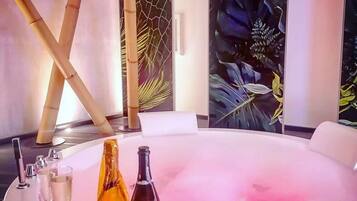 Relax in a serene spa setting with a large hot tub surrounded by a minimalist design and a beautiful floral mural.