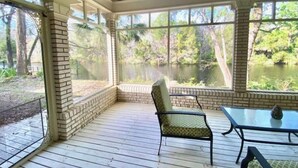 A covered outdoor area with a wooden deck, a chair, and a table. - Oak Rock Ranch - Riverfront - Scenic Old Florida (Inglis)