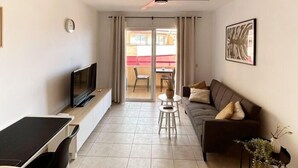 A modern living room with a flat-screen TV, a sofa, a dining table, and a ceiling fan. - Relax Oasis of the Sea, Santiago del Teide (Puerto Santiago)