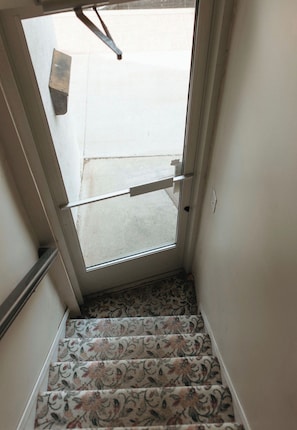 A staircase with patterned carpet leading to a door with a metal handle.