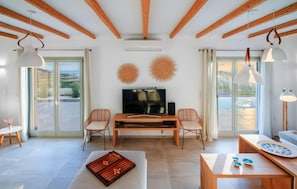 A spacious living area with a TV, two wicker chairs, a coffee table, and a board game. - Villa Flo by Anamnesia Collection (Naxos)