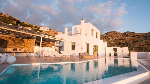 A modern white building with a swimming pool, outdoor seating, and a mountainous backdrop. - Villa Flo by Anamnesia Collection (Naxos)