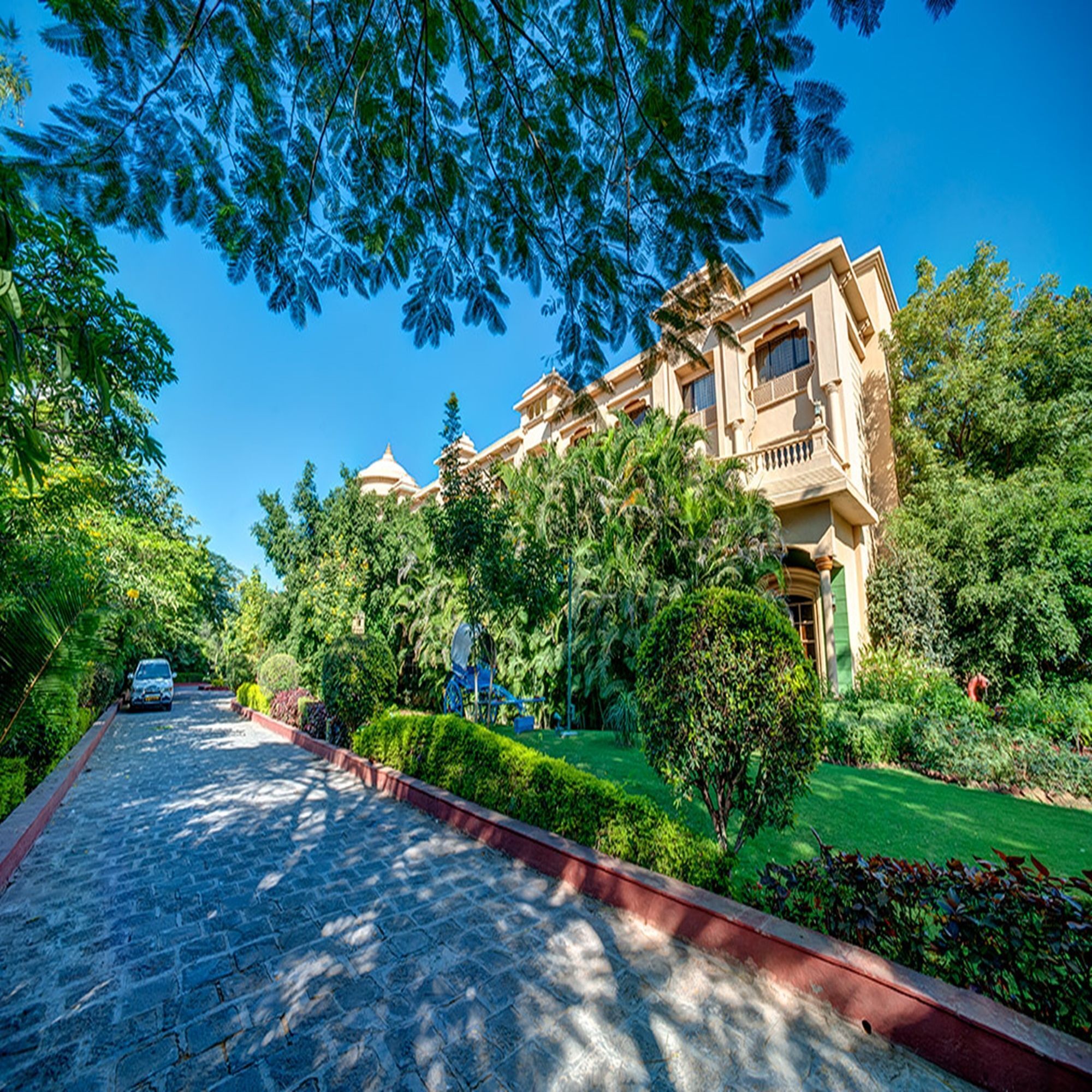 A large, historic building with multiple domes and a well-maintained garden.