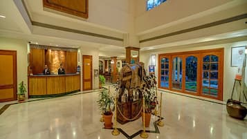 A spacious lobby with a reception desk, a large decorative centerpiece, and a view of the outdoors through large windows.
