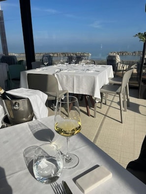 A dining table with a wine glass and a pitcher, set against a backdrop of a scenic view. - Vineyard Farmhouse in Massignano - just minutes from the beach (Massignano)