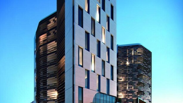 Un immeuble moderne de grande hauteur, doté d’une conception architecturale originale, caractérisée par une série de fenêtres rectangulaires et une façade incurvée.