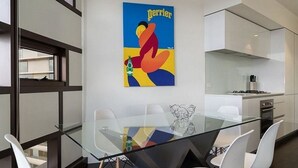 Une cuisine moderne avec une table à manger en verre et des chaises blanches.