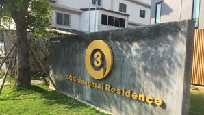 A sign for 3Q Chiangmai Residence with a large number '3' and the name '3Q Chiangmai Residence' in gold lettering on a grey background.