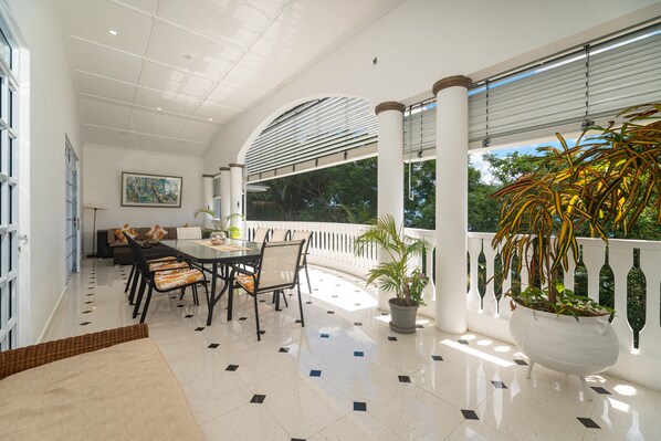 A spacious patio with a dining area, a sofa, and a potted plant. - Luxurious 2-bed Villa in Bel Ombre Mahe Seychelles (Mahé Island)