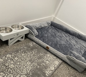 Guests can relax with their pets in this cozy corner, featuring a pet bed with water bowl and feeding station.