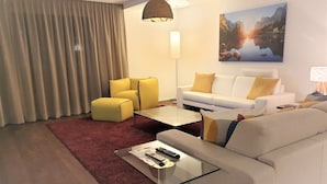 A modern living room with a glass coffee table, a sofa, a yellow armchair, and a white couch. - Swiss Hotel Apartments Interlaken (Interlaken)