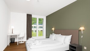 A modern hotel room with a large bed, a desk, and a chair. - Swiss Hotel Apartments Interlaken (Interlaken)
