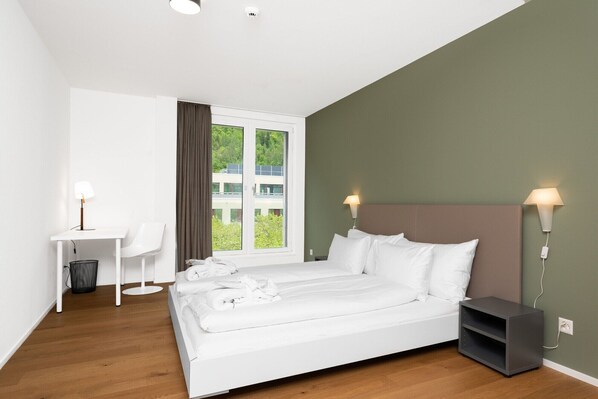 Une chambre d’hôtel moderne, dotée d’un grand lit, d’un bureau et d’une chaise.