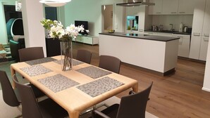 A modern kitchen with white cabinets, a stainless steel range hood, and a central island with a sink. - Swiss Hotel Apartments Interlaken (Interlaken)