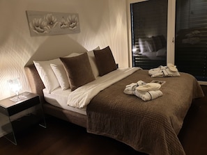 A neatly made bed with a brown blanket, white pillows, and a bedside table with a lamp. - Swiss Hotel Apartments Interlaken (Interlaken)