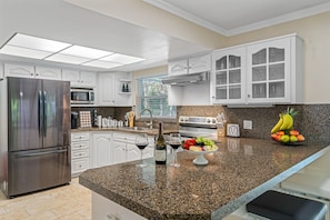 A modern kitchen with white cabinetry, stainless steel appliances, and a granite countertop. - Spacious & Amazing Home w/ Big Pool and Patio (Brandon)