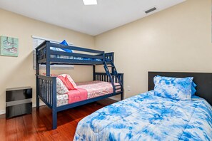 A bunk bed with a blue and white patterned bedspread, a small bedside table, and a wall-mounted heater. - Spacious & Amazing Home w/ Big Pool and Patio (Brandon)
