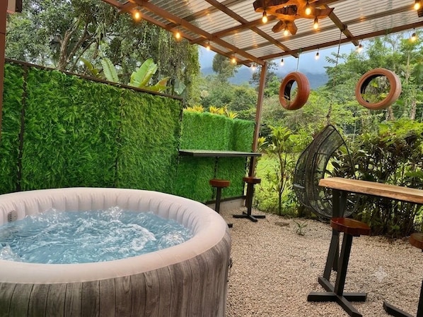 A hot tub, wooden table, and hanging tire swings in a garden setting.