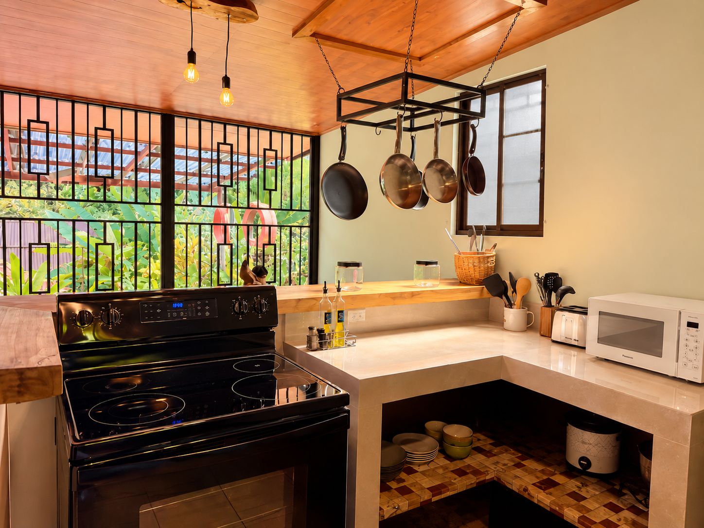 A kitchen with a stove, microwave, and hanging pots.