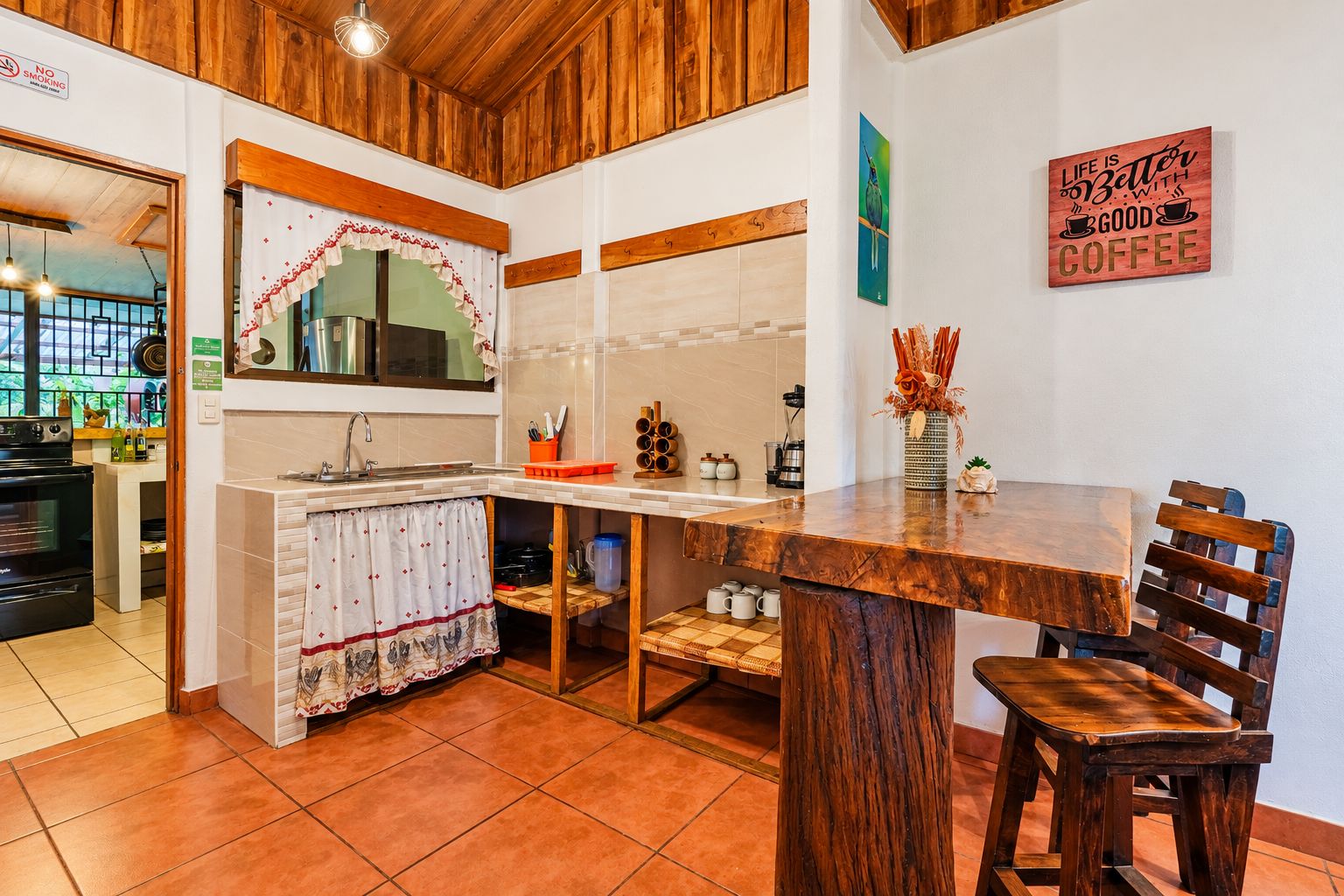 A kitchen with a wooden countertop, a sink, and a dining area with a wooden table and chairs.