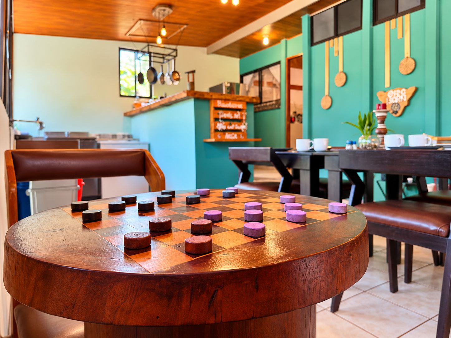 A round wooden table with a chessboard in a cafe setting.