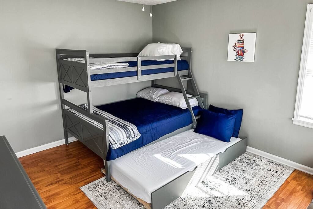 A bunk bed room with grey walls, a patterned rug, and a framed picture on the wall.