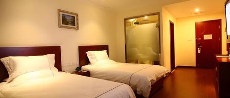 Habitación de hotel con dos camas, un cuadro en la pared, una puerta con espejo y suelo de madera.