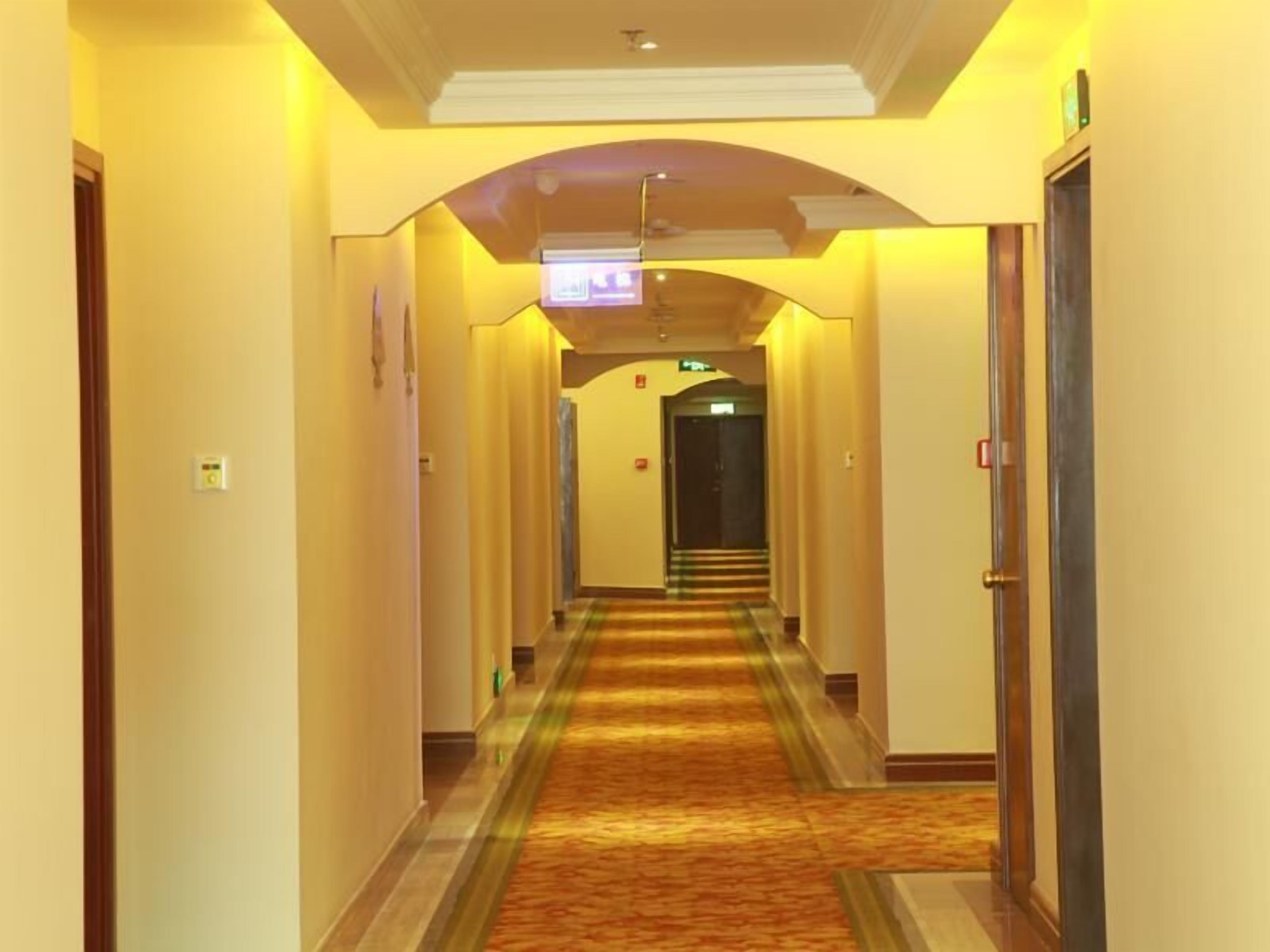 Un pasillo de hotel con piso alfombrado, puertas a ambos lados y una lámpara en el techo.