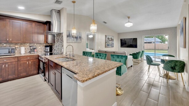 A modern kitchen with granite countertops, stainless steel appliances, and a central island. - Casa De Paradiso - Modern yet comfy home at the center of it all! (Kissimmee)