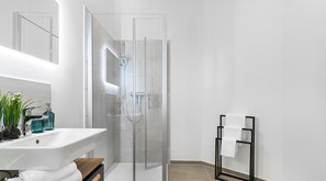 A modern bathroom with a glass-enclosed shower, a white sink with a wooden countertop, and a towel rack with towels. - Strandgut - Ground Fl., Terrace, Garden Furniture, Barbecue, Shower, TV, Parking (Gelting)