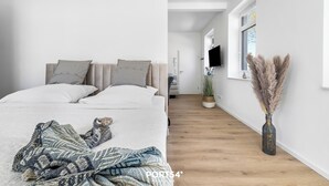Een moderne slaapkamer met een bed, kussens en een deken. Een gang leidt naar een badkamer met een douche en een raam.