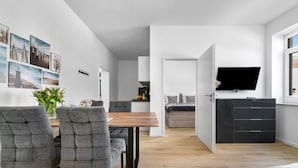 A modern living space with a dining area, kitchen, and a TV mounted on the wall. - Strandläufer - Shower, TV, Terrace, Garden Furniture, Grill, Parking Space (Gelting)