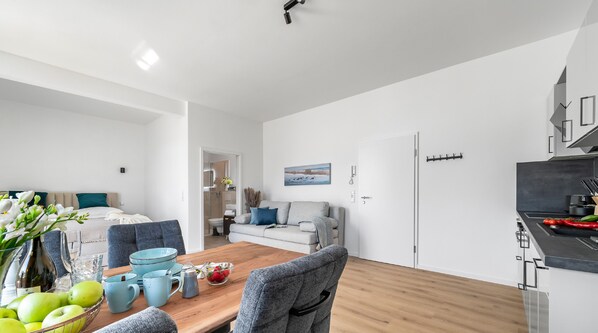 A modern apartment with a dining area, a living room, and a kitchen.