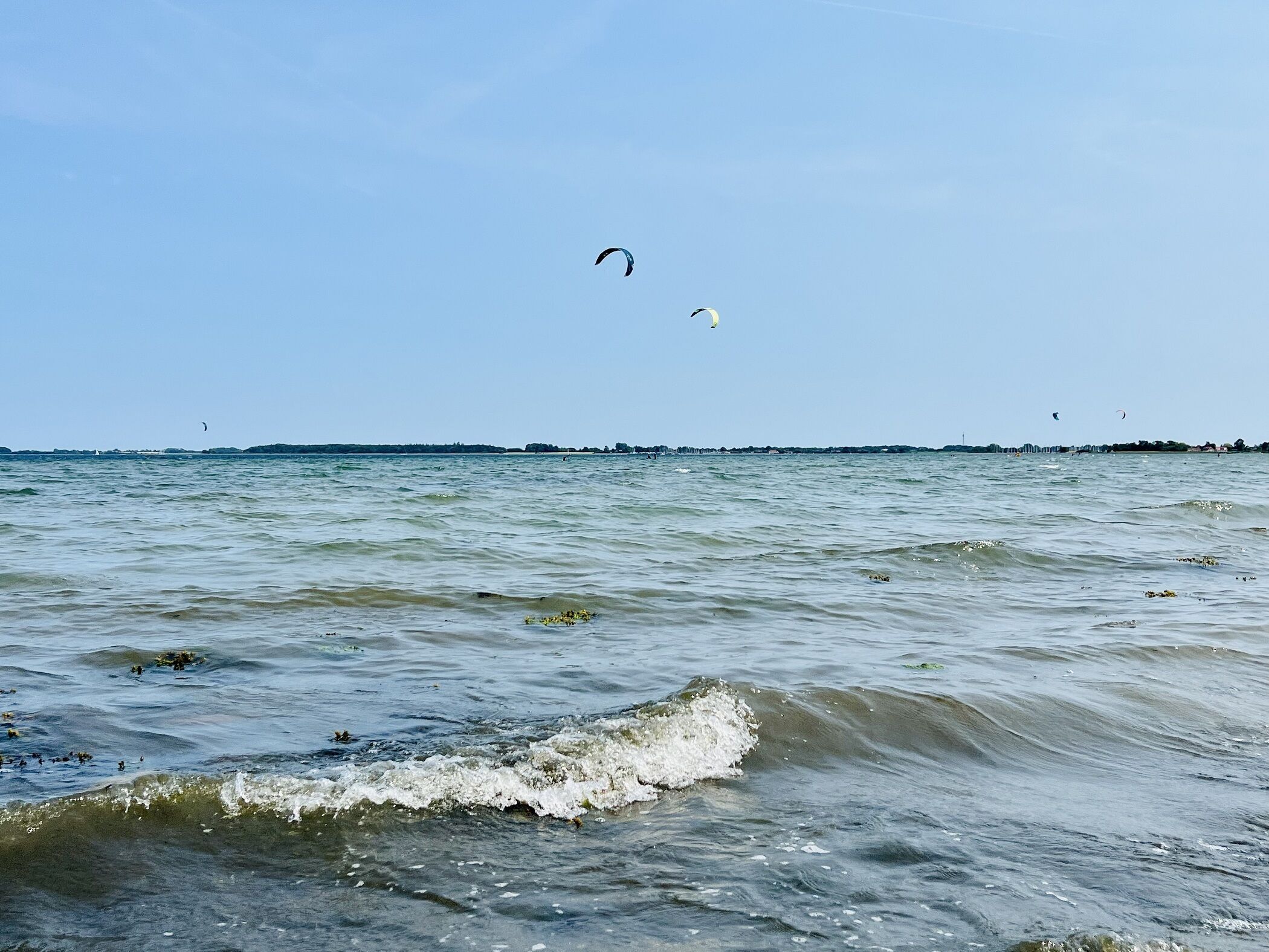 Een uitzicht op een strand met golven en vlieger in de lucht.