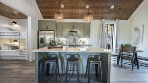 A modern kitchen with a central island, bar stools, and pendant lighting.