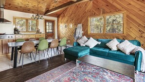 Un interior de cabaña acogedor con comedor, sofá y cocina.