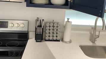 A kitchen with a microwave, stove, sink, and a drawer with utensils.