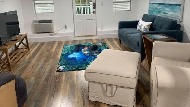 Ein gemütliches Wohnzimmer mit Holzboden, einem großen Gemälde, einer Couch und einem Fernseher.