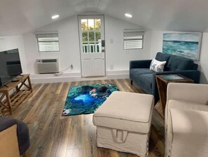 Relax in a spacious room with a high ceiling, featuring a large floor, colorful rug, and comfortable sofa.