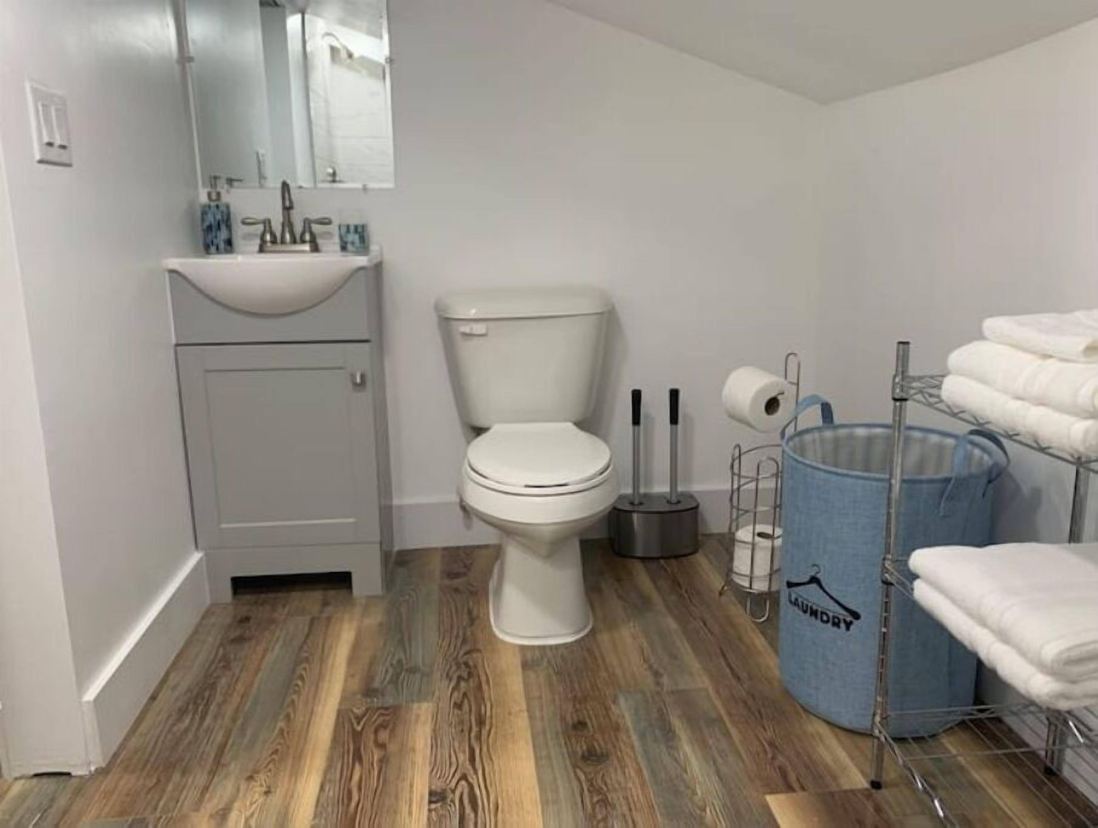 Une salle de bain avec des toilettes, un lavabo et un panier à linge bleu.
