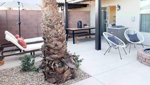 Patio esterno con pergola, posti a sedere e una palma.